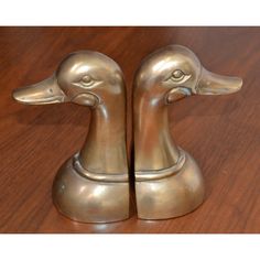 two metal ducks sitting on top of a wooden table