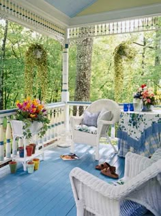 a porch with white wicker furniture and flowers on the table in front of it