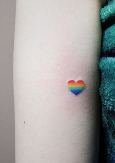 a small rainbow heart tattoo on the arm