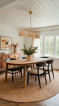 a dining room table with four chairs and a rug on the floor in front of it