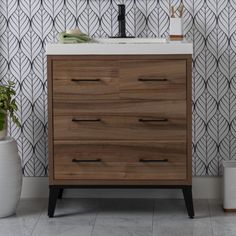 a bathroom vanity with wooden drawers and white counter top next to potted plants on the floor