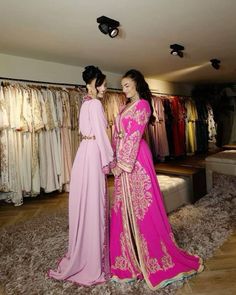 two women in pink and gold dresses looking at each other's clothes on racks