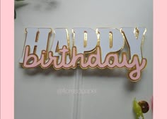 a birthday cake topper with the word happy on it in pink and gold foil