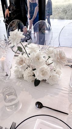 the table is set with white flowers and silverware