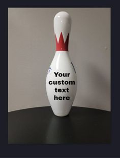 a white bowling ball with a red crown on it sitting on top of a table