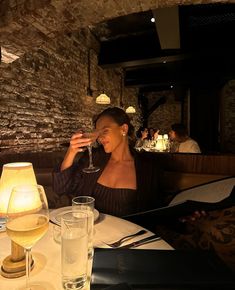 a woman sitting at a table with a glass of wine in front of her face