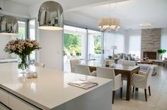 a kitchen and dining room with large windows in the backround, white furniture on both sides