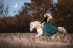 a woman riding on the back of a white horse in a field next to trees