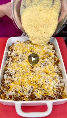 someone is adding cheese to a casserole dish