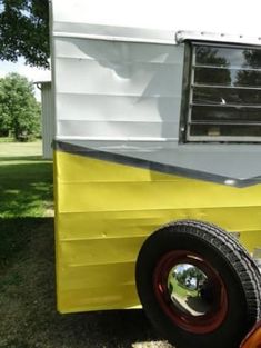 an old yellow and white trailer parked in the grass