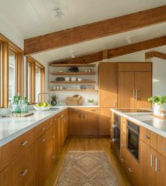 a kitchen with wooden cabinets and white counter tops, along with an area rug on the floor