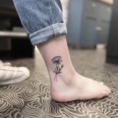 a person with a small tattoo on their foot that has a dandelion in it