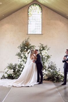 a bride and groom kissing in front of an altar