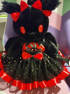 a black teddy bear wearing a red and black dress with stars on it's chest