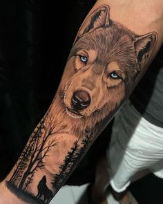 a man's arm with a wolf and trees tattoo on the left side of his arm