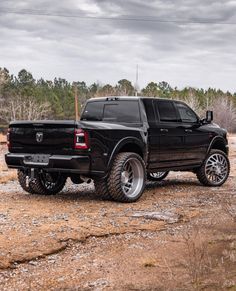 a black truck parked on top of a dirt field