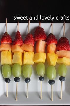 fruit skewers with strawberries, grapes, and melon are arranged on a white plate