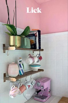 a kitchen with pink walls and shelves filled with coffee cups, mugs and other items