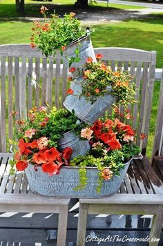 two buckets filled with flowers sitting on top of a wooden bench