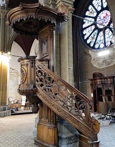 an ornate wooden staircase in front of a stained glass window