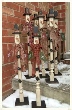 three snowmen with hats and scarfs are standing in front of a brick wall