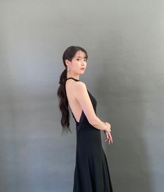 a woman in a long black dress poses for the camera with her hand on her hip