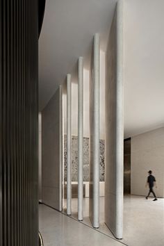 a person walking past tall columns in a building