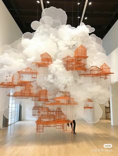 a person standing in front of a large cloud filled with orange and white buildings on top of wooden floors