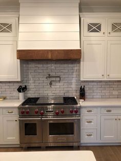 a stove top oven sitting inside of a kitchen next to white cabinets and counter tops