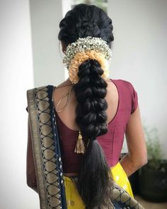 a woman with long black hair wearing a yellow sari and a braid in her hair