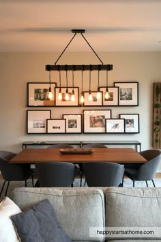 a dining room table with chairs and pictures hanging on the wall above it in front of a couch