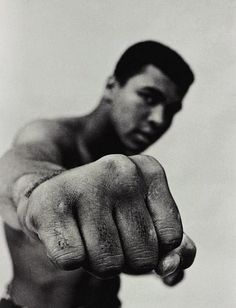 a black and white photo of a man pointing at the camera with his fist out