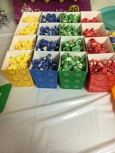 there are many different colored candies in small boxes on the table next to each other