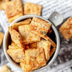 a bowl filled with crackers sitting on top of a table next to other pieces of food