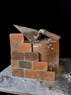 an old brick wall with a hammer stuck in it and some bricks on the ground