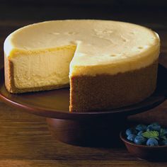 a cheesecake with one slice cut out on a plate next to some blueberries