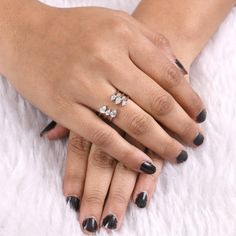 a woman's hands with black and white manicures holding onto her engagement ring