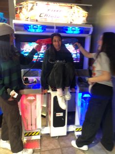 three people standing in front of a vending machine with neon lights on the sides