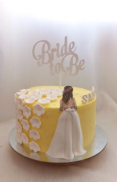 a yellow and white wedding cake with a bride and groom topper sitting on it