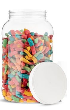 a glass jar filled with lots of colorful candies next to a white plastic lid