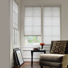 a living room filled with furniture and two windows covered in shades of white blindes