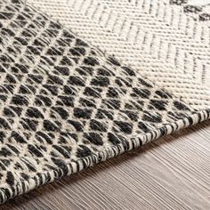 an animal print rug on top of a wooden floor next to a white and black area rug