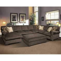 a large sectional couch in a living room with lots of pillows on top of it