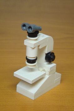 a toy microscope sitting on top of a wooden table next to a black and white object