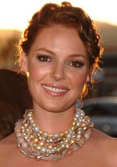 a woman wearing a necklace with pearls on it