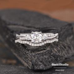 a white gold engagement ring set with two diamonds on top of a black stone slab