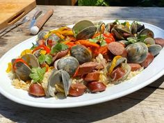 a white plate topped with lots of food on top of a wooden table next to utensils