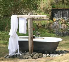 an old bathtub with towels hanging over it and a glass of wine in the tub