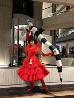 a woman in a red dress is posing with a large black and white striped pole