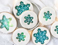 several decorated cookies on a plate with frosting and icing snowflakes